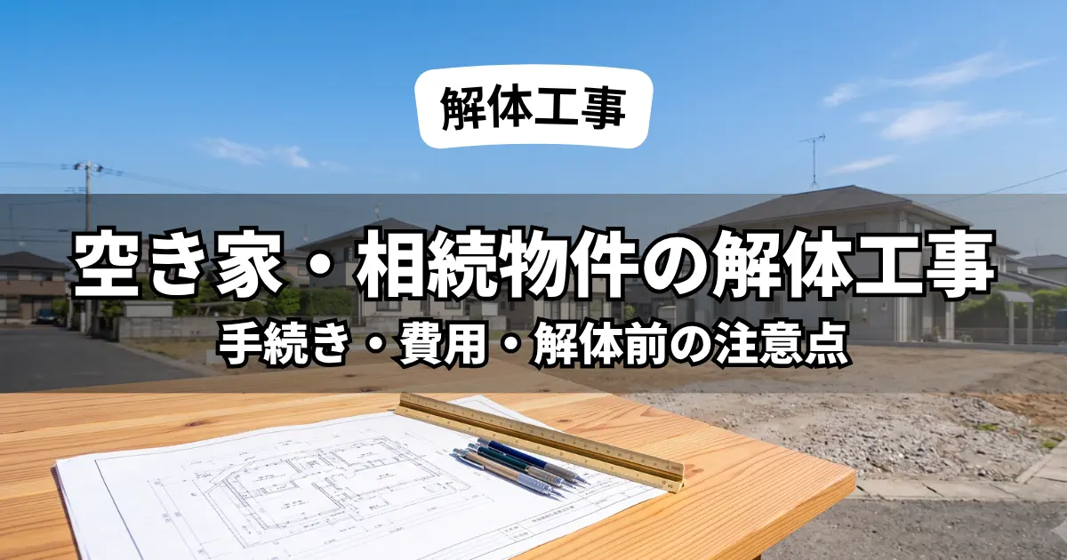 木製テーブルの上の解体・建築図面と、その奥に広がる、空き家の解体工事が完了し綺麗に整地された更地。相続物件や空き家処分の手続き・計画のイメージ。