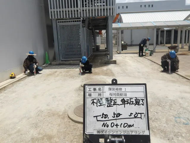 路盤の不陸整正を行いレベル測定と転圧を進める作業員