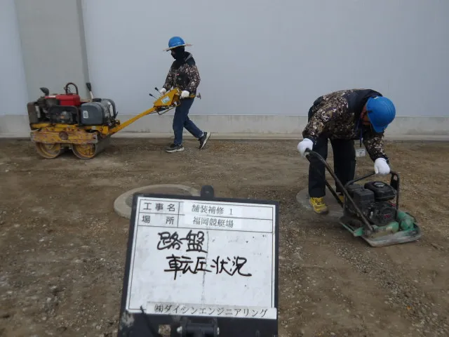 転圧機を用いて舗装下の路盤をしっかり締め固める作業状況