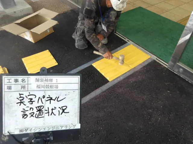 建物出入口の舗装面に視覚障がい者用点字パネルを設置する作業