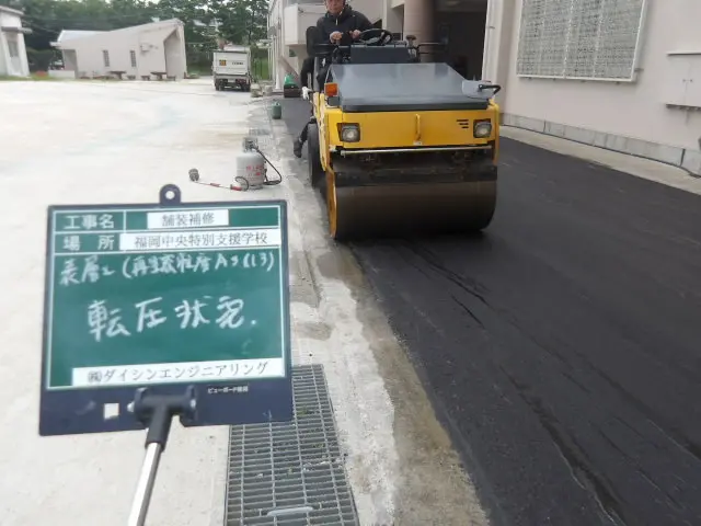 重機でアスファルト舗装面を転圧して締め固める作業