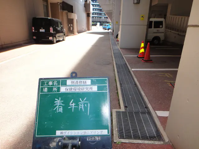 駐車場内の柱に接する修繕前の側溝とグレーチング