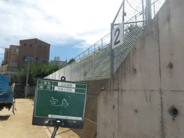 平尾小学校の法面補修完成、新設フェンスと緑化した斜面